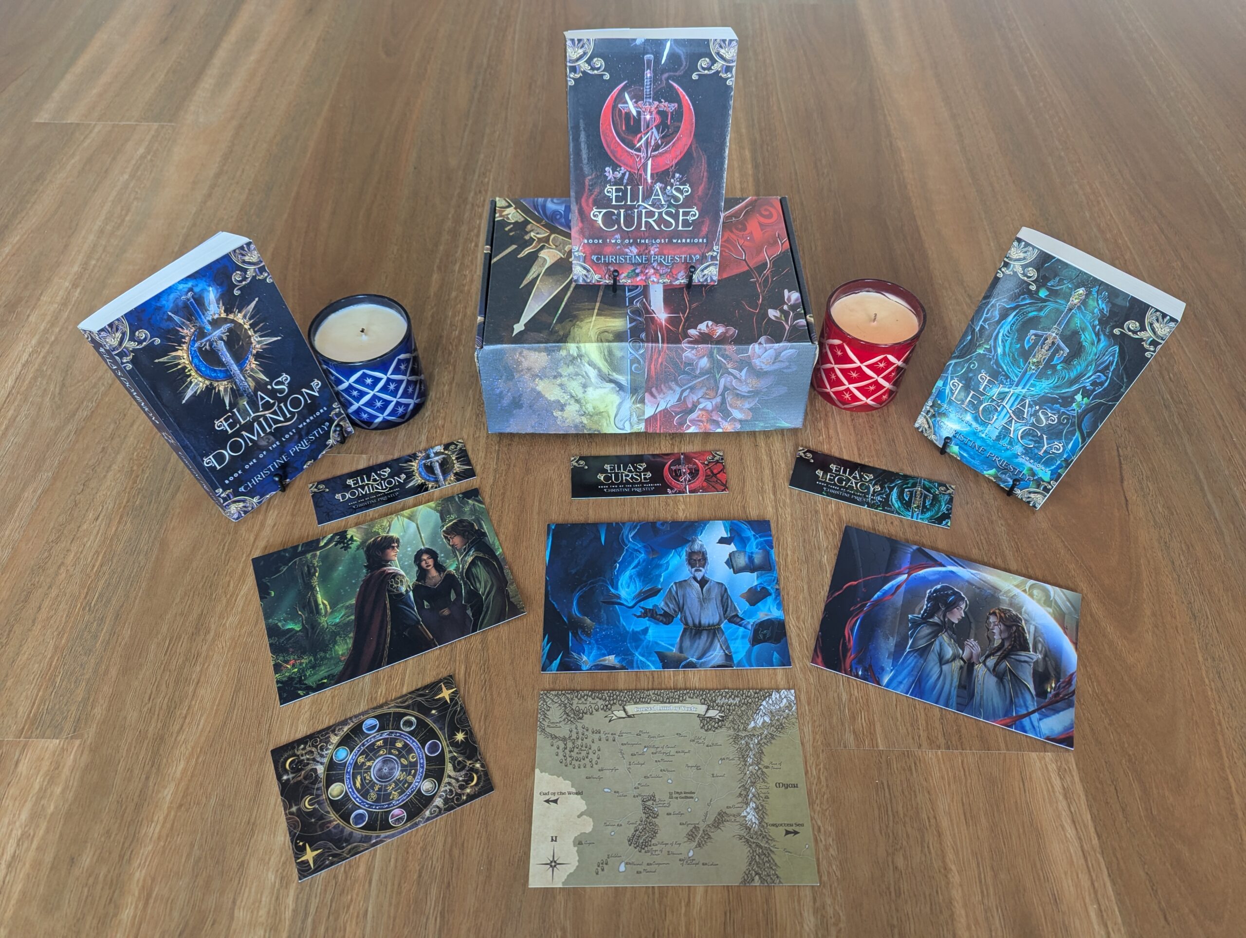 Photograph of Deluxe Book Bundle including paperbacks of Ella's Dominion, Ella's Curse, Ella's Legacy, bookmarks, candles, custom gift box, concept artwork and map